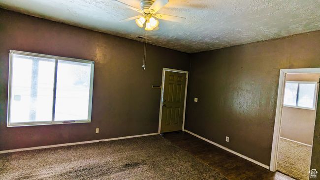 Carpeted spare room with ceiling fan and a textured ceiling | Image 32