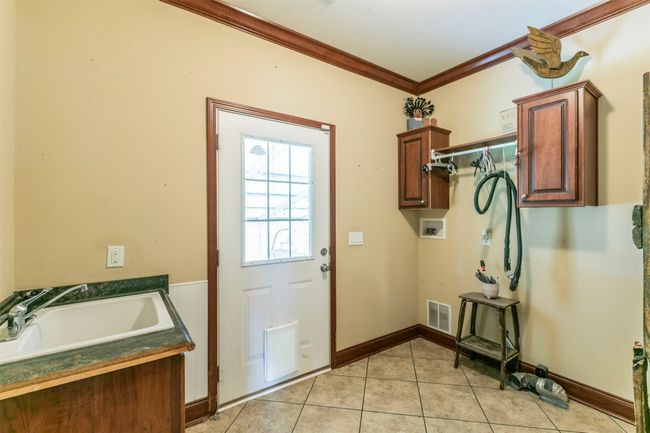 Doorway to outside with visible vents, a sink, light tile patterned floors, baseboards, and ornamental molding | Image 21