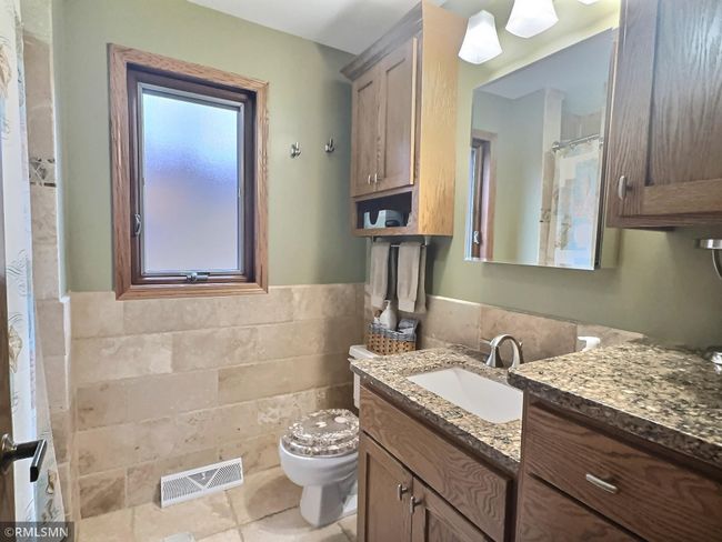 The main floor full bathroom has updated cabinets and granite countertops. Tile flooring and tub/shower surround. | Image 24