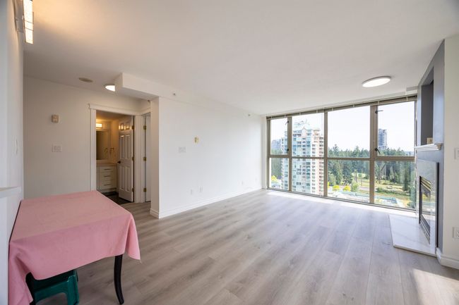 Unfurnished dining area featuring expansive windows, light wood-type flooring, a glass covered fireplace, and a view of city | Image 7