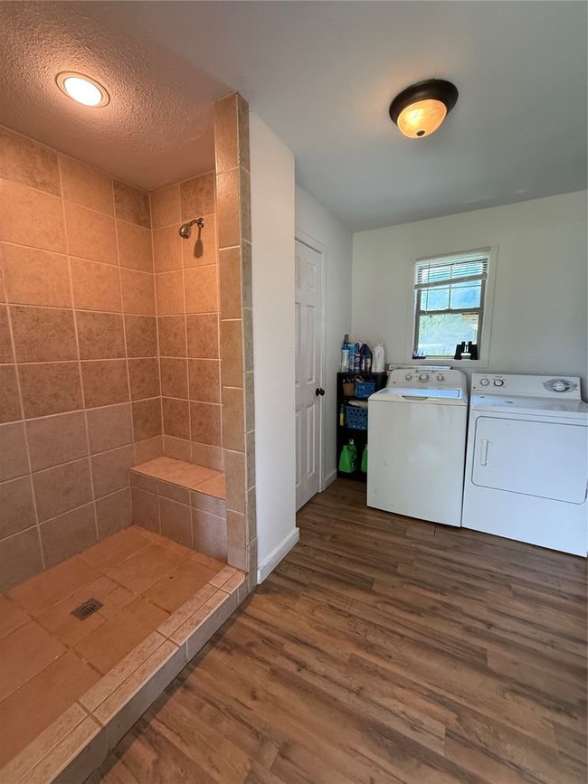 Full bath featuring dark wood-style flooring, a shower stall, separate washer and dryer, and a textured ceiling | Image 20
