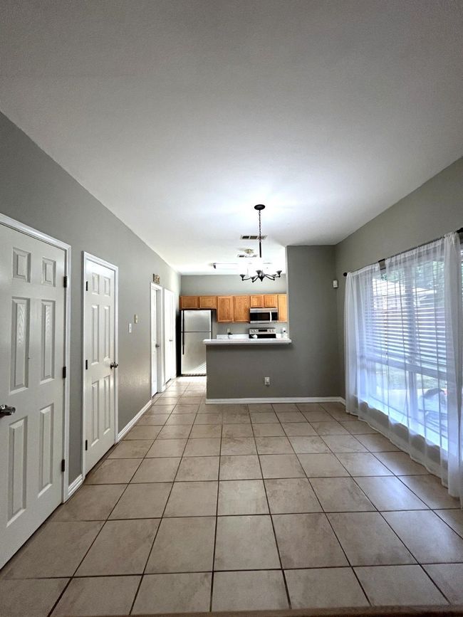 Kitchen with stainless steel appliances, light tile patterned floors, a chandelier, and a peninsula | Image 7