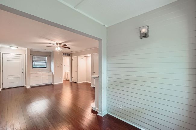 Unfurnished living room featuring dark wood-style flooring, visible vents, baseboards, and ceiling fan | Image 9