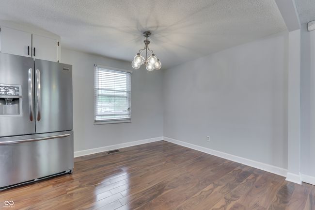 unfurnished dining area with dark wood-style floors, a chandelier, visible vents, baseboards, and a textured ceiling | Image 9