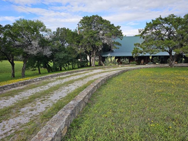 Portion of the long rock-wall- lined circular drive in front of the home | Image 4