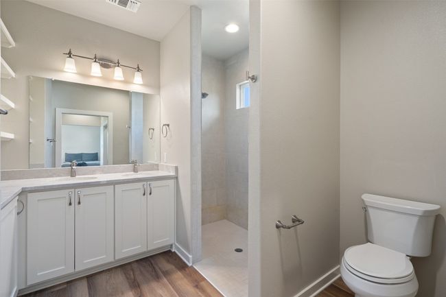 Bathroom featuring double vanity, a walk in shower, wood finished floors, and toilet | Image 36