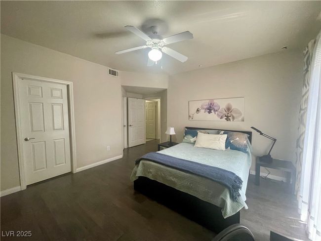Bedroom with dark wood-type flooring, visible vents, baseboards, and ceiling fan | Image 28
