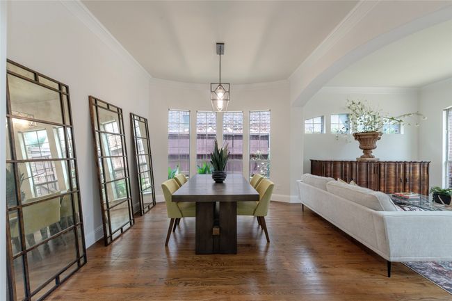 Dining area featuring crown molding, wood finished floors, and arched walkways | Image 8
