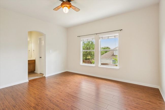 Empty room with arched walkways, a ceiling fan, and light wood-style flooring | Image 23