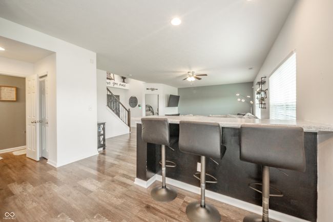 kitchen featuring light wood finished floors, a kitchen bar, a ceiling fan, baseboards, and recessed lighting | Image 16