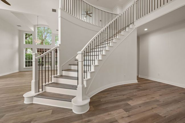 Staircase with baseboards, visible vents, a high ceiling, and wood finished floors | Image 5