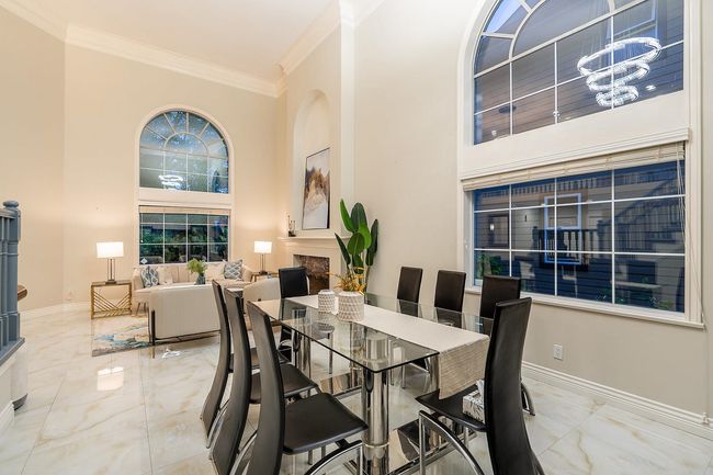 Dining space featuring ornamental molding, marble tiled floors, a chandelier, a towering ceiling, and a fireplace | Image 8