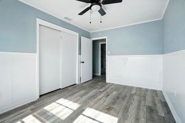 Unfurnished bedroom featuring wood finished floors, a closet, ornamental molding, and a ceiling fan | Image 20
