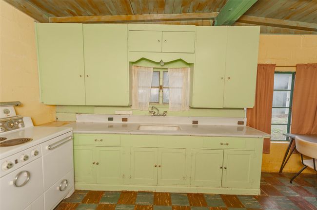Kitchen with wooden ceiling, light countertops, a sink, range with electric stovetop, and green cabinetry | Image 26