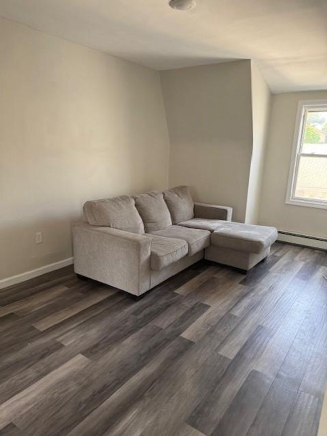 Living area featuring a baseboard heating unit and dark wood-style floors | Image 9