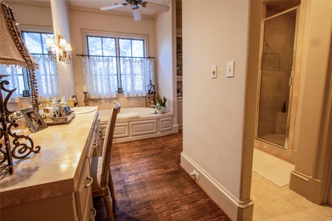 Full bathroom with plenty of natural light, a bath, ceiling fan with notable chandelier, and a shower stall | Image 13