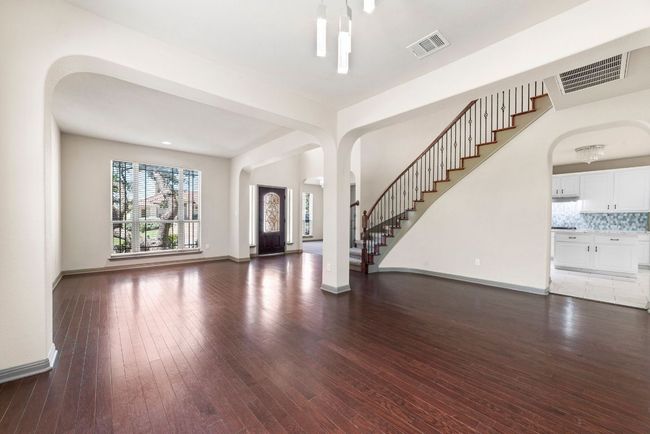 Unfurnished living room featuring arched walkways, dark wood-style flooring, and stairs | Image 7