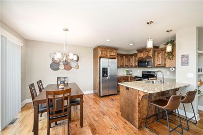 Kitchen with kitchen peninsula, appliances with stainless steel finishes, light stone countertops, and light wood-type flooring | Image 3