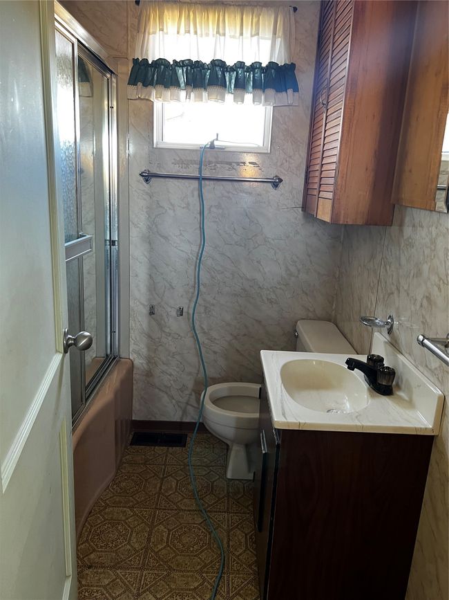 Full bathroom featuring tile patterned floors, vanity, toilet, and shower / bath combination with glass door | Image 63