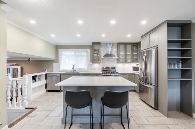 Kitchen with gray cabinetry, wall chimney exhaust hood, a sink, and stainless steel appliances | Image 8