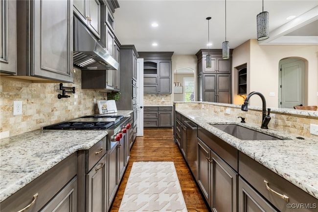 Kitchen featuring arched walkways, dark wood-style floors, light stone counters, and recessed lighting | Image 13
