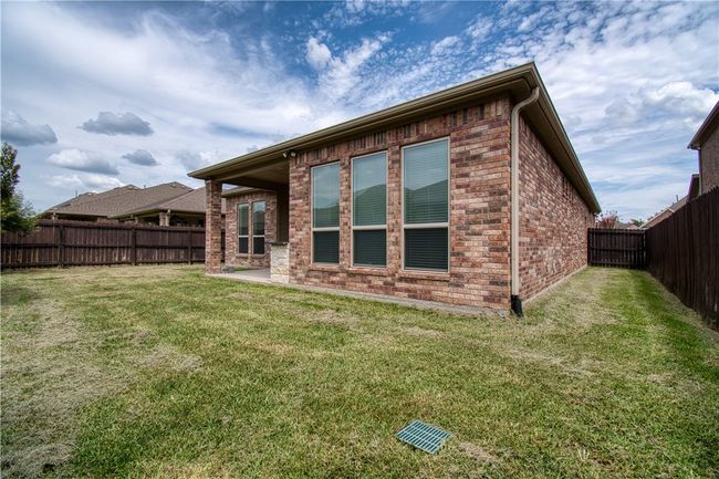 Back of house featuring a fenced backyard, a lawn, a patio, and brick siding | Image 22