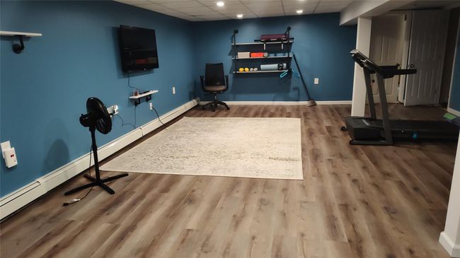 Exercise area with a drop ceiling, wood finished floors, baseboards, recessed lighting, and baseboard heating | Image 5