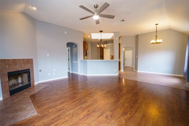 Living room featuring a chandelier, arched walkways, a tiled fireplace, and vaulted ceiling | Image 11