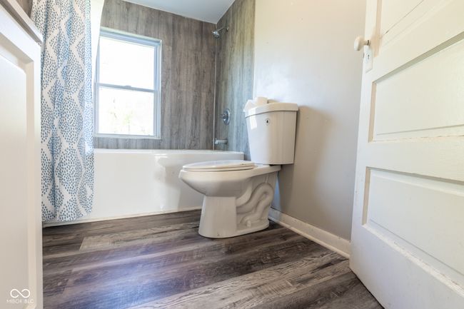 full bathroom with toilet, wood finished floors, and shower / tub combo with curtain | Image 32