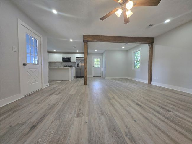 Unfurnished living room with light wood-style flooring, recessed lighting, ceiling fan, and beamed ceiling | Image 7