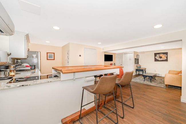 Kitchen with a wall mounted AC, a kitchen bar, wood finished floors, recessed lighting, and butcher block countertops | Image 16