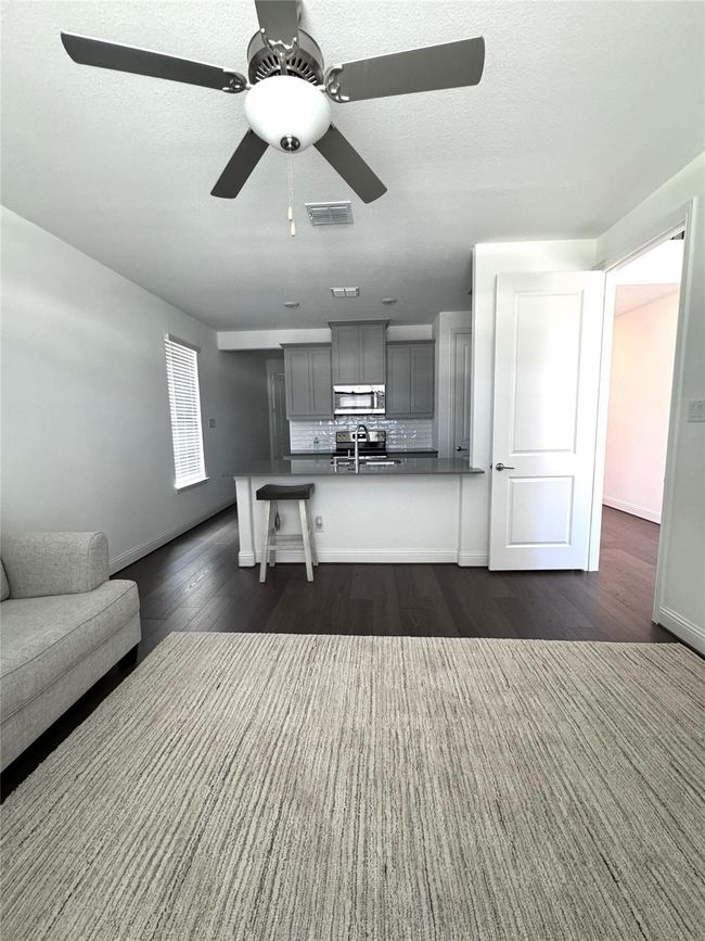 Living area with dark wood-style floors and a ceiling fan | Image 11
