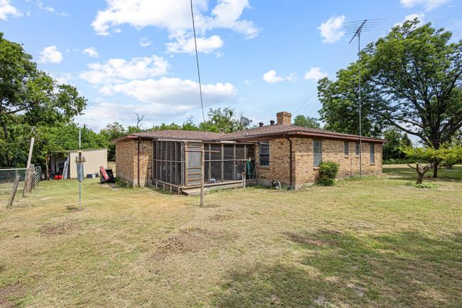 Back of property with a screened in porch, brick siding, a chimney, and a storage unit | Image 33