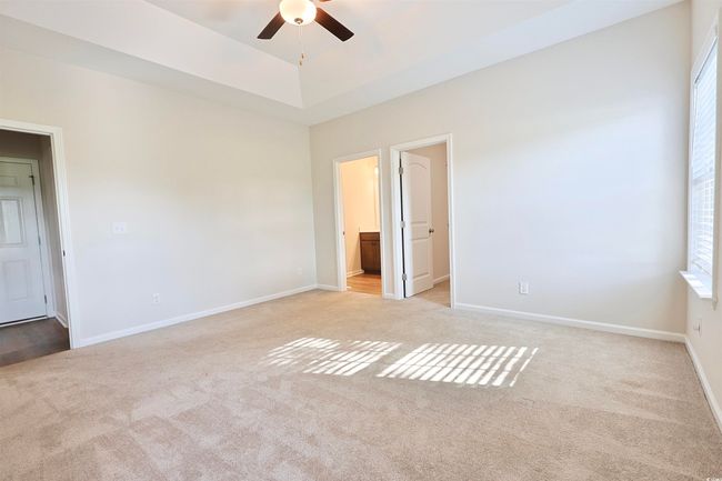 Carpeted spare room with ceiling fan, healthy amount of natural light, and a tray ceiling | Image 11