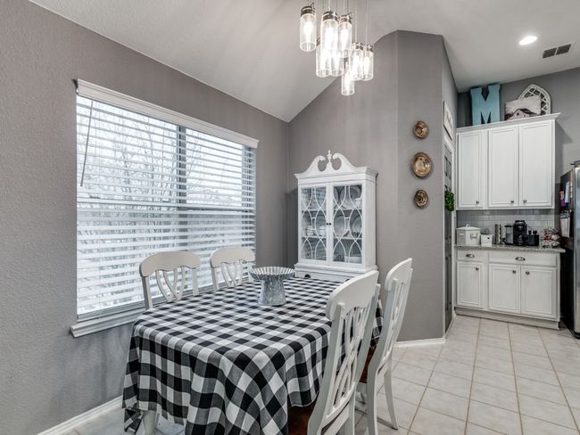 Dining room with light tile patterned floors, baseboards, vaulted ceiling, a textured wall, and a chandelier | Image 12