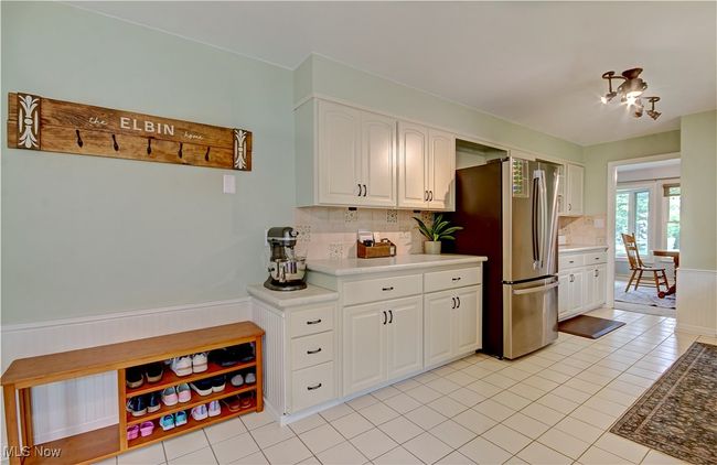 Kitchen with wainscoting, freestanding refrigerator, backsplash, white cabinets, and light countertops | Image 19