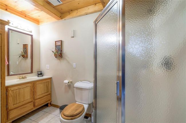Bathroom featuring a stall shower, tile patterned flooring, vanity, and a wooden ceiling with exposed beams | Image 40