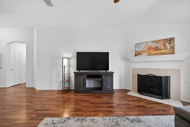 Living area with a tile fireplace, wood finished floors, and arched walkways | Image 21