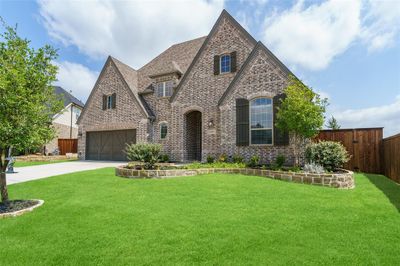 English style home featuring a beautifully landscaped front lawn. | Image 1