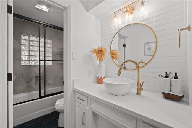 Designer bathroom with gold fixtures, vessel sink, and round accent mirror. | Image 33