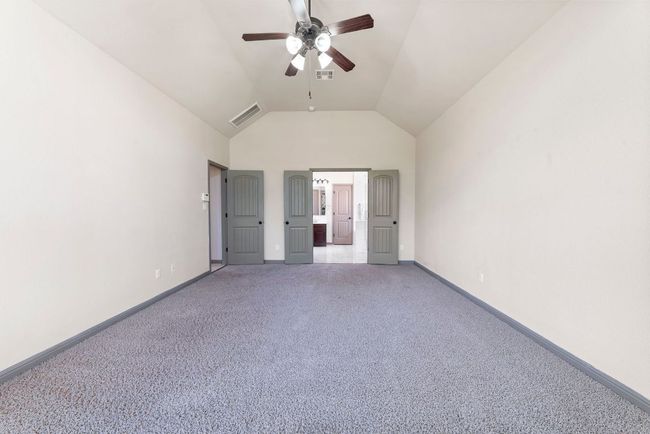 Unfurnished bedroom with light colored carpet, high vaulted ceiling, ensuite bathroom, and ceiling fan | Image 21
