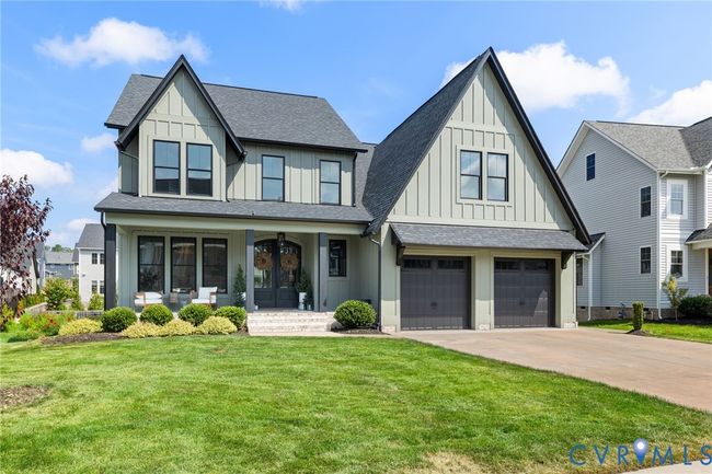 View of front facade featuring a shingled roof, board and batten siding, concrete driveway, and covered porch | Image 8