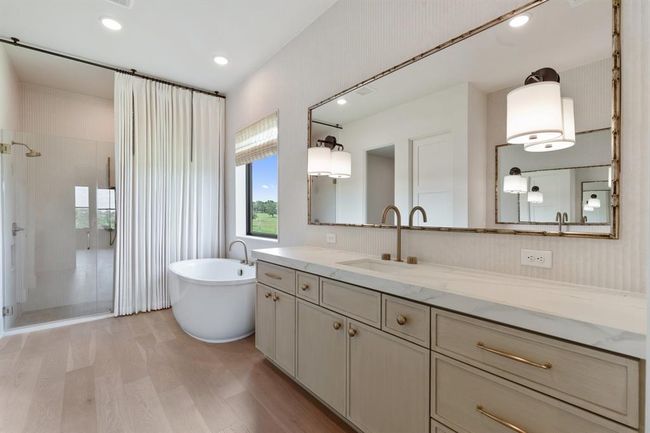 The elongated soaking tub is tucked beneath a large picture window. While natural light pours into the space, one can rest and view the green pastures just outside of the window. An oversized shower repeats Kohler's elegant plumbing trim and features a niche for toiletries and a large bench. Two shower heads offer options for the user. | Image 20