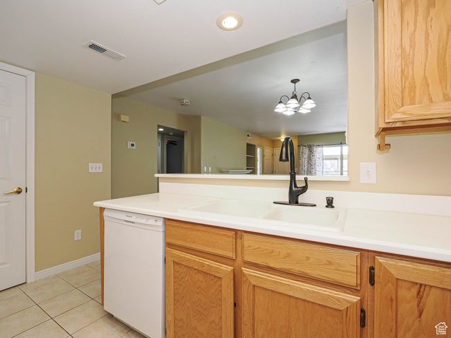 Kitchen with a peninsula, a sink, visible vents, white dishwasher, and light tile patterned floors | Image 11