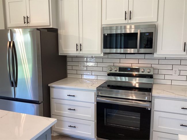 Kitchen with stainless steel appliances, white cabinets, and tasteful backsplash | Image 12