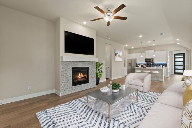 Living area with a ceiling fan, light wood finished floors, a glass covered fireplace, recessed lighting, and vaulted ceiling | Image 17