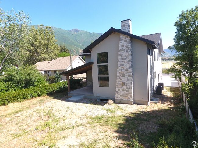 Back of property featuring stucco siding, stone siding, a chimney, and a mountain view | Image 45