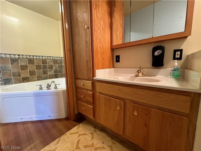 Bathroom featuring hardwood / wood-style flooring, vanity, and a bath to relax in | Image 17