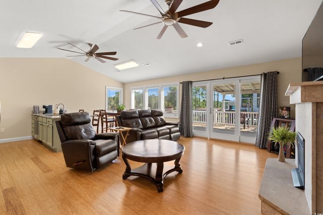 Living room with vaulted ceiling, ceiling fan, light wood finished floors, a premium fireplace, and recessed lighting | Image 5