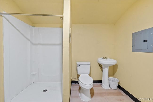 Bathroom featuring electric panel, a stall shower, baseboards, toilet, and wood finished floors | Image 34